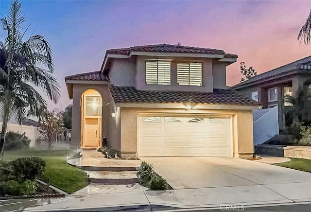 view of front of property with concrete driveway, fence, a tile roof, and stucco siding