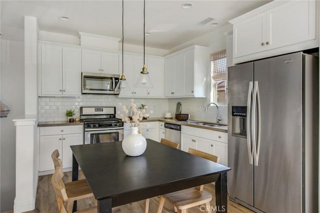 kitchen featuring sink, pendant lighting, appliances with stainless steel finishes, and white cabinets