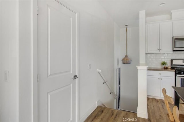 kitchen featuring white cabinets, appliances with stainless steel finishes, tasteful backsplash, hanging light fixtures, and butcher block countertops