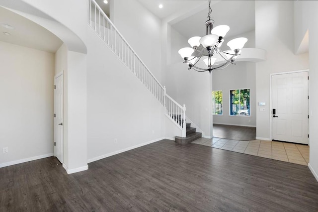 entrance foyer featuring hardwood / wood-style floors, a towering ceiling, and an inviting chandelier