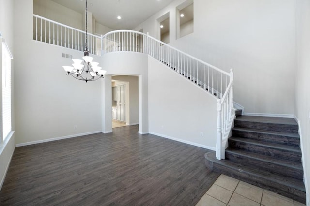 staircase featuring a chandelier, a towering ceiling, and wood-type flooring