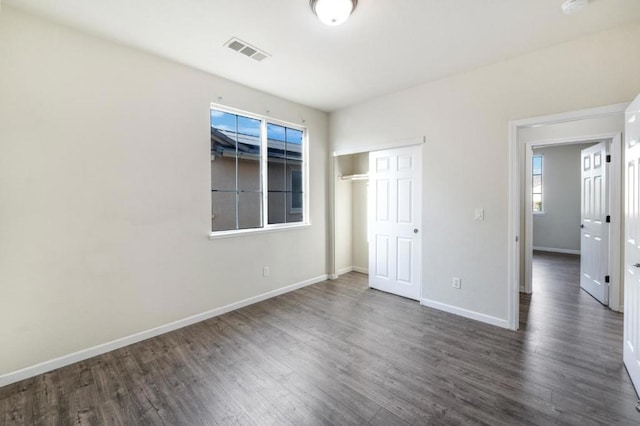 unfurnished bedroom with a closet and dark hardwood / wood-style floors