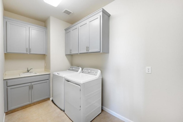 clothes washing area featuring sink, washing machine and clothes dryer, and cabinets