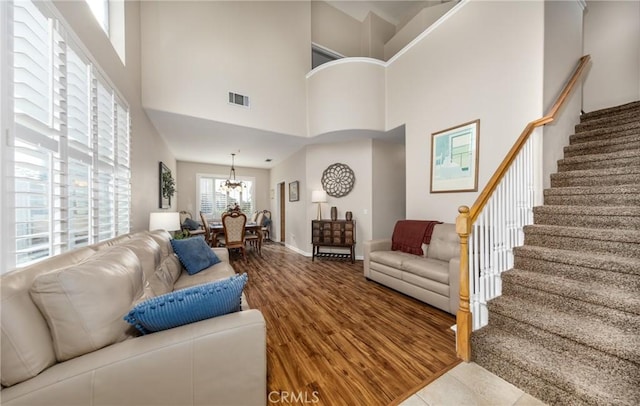 living room with hardwood / wood-style flooring, an inviting chandelier, and a high ceiling