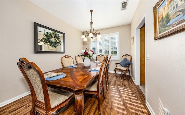 dining area with dark wood-type flooring and an inviting chandelier