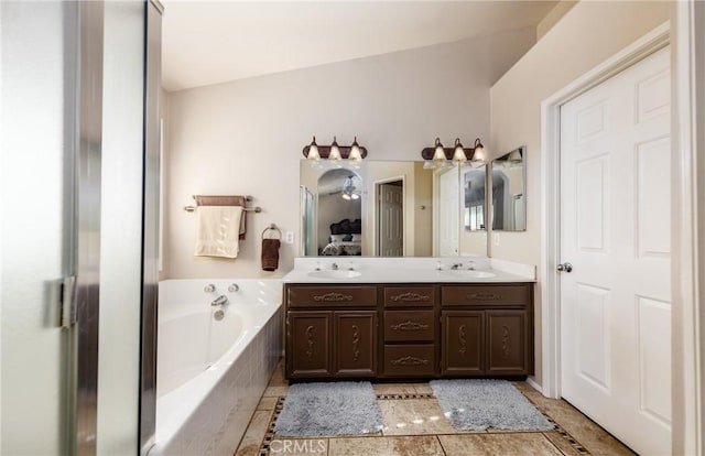 bathroom with tile patterned floors, vanity, tiled bath, vaulted ceiling, and ceiling fan