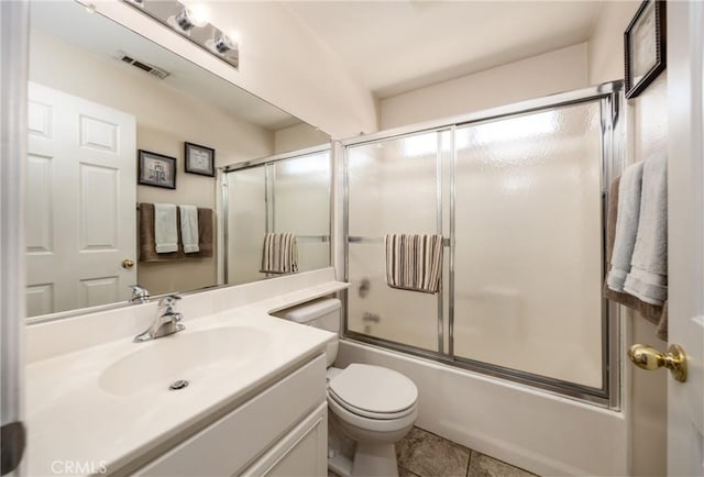 full bathroom featuring toilet, vanity, tile patterned flooring, and combined bath / shower with glass door