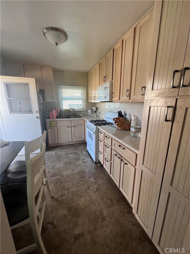 kitchen with sink, light brown cabinetry, and white appliances