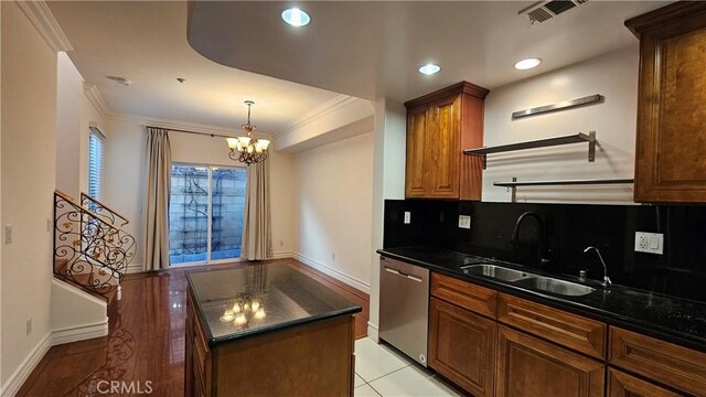 kitchen featuring an inviting chandelier, sink, dark stone countertops, stainless steel dishwasher, and a center island