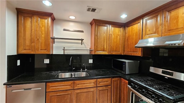 kitchen featuring stainless steel appliances, tasteful backsplash, dark stone counters, and sink