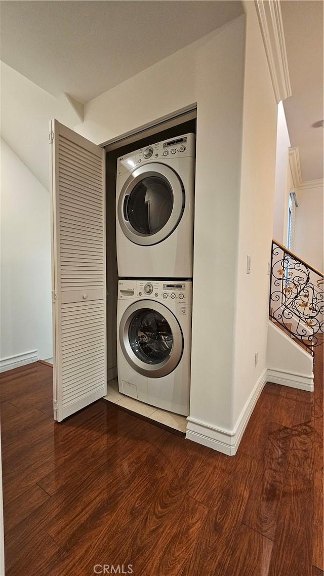 laundry room with stacked washing maching and dryer and dark wood-type flooring