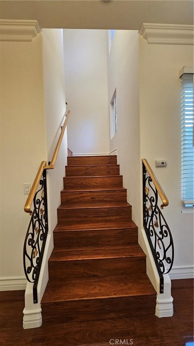 stairs featuring wood-type flooring and ornamental molding