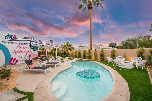 pool at dusk featuring a patio