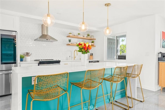 kitchen with stainless steel electric stove, pendant lighting, wall chimney range hood, white cabinetry, and backsplash