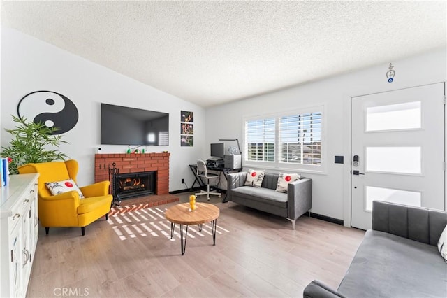 living room featuring lofted ceiling, a fireplace, a textured ceiling, and light hardwood / wood-style floors