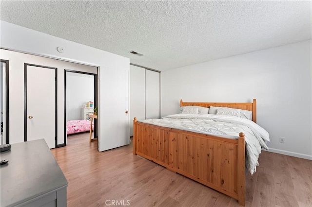 bedroom with a textured ceiling and light hardwood / wood-style flooring