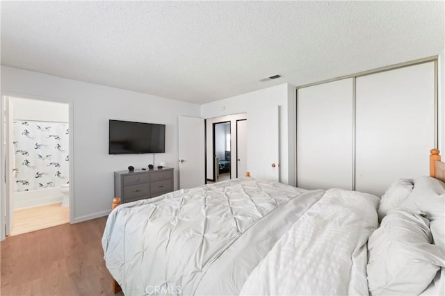 bedroom featuring ensuite bathroom, a closet, a textured ceiling, and hardwood / wood-style floors