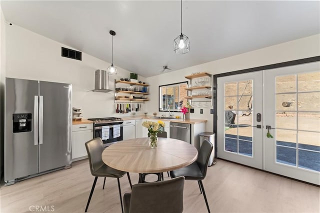 dining room with vaulted ceiling, light hardwood / wood-style floors, french doors, and sink