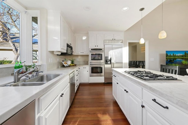 kitchen with pendant lighting, sink, dark wood-type flooring, appliances with stainless steel finishes, and white cabinetry