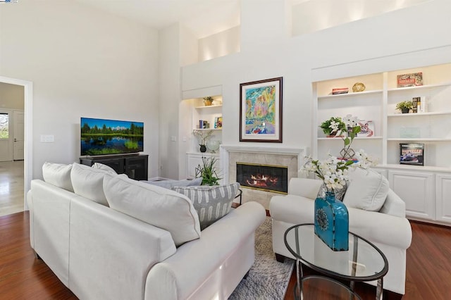 living room with a fireplace, built in features, dark hardwood / wood-style floors, and a high ceiling