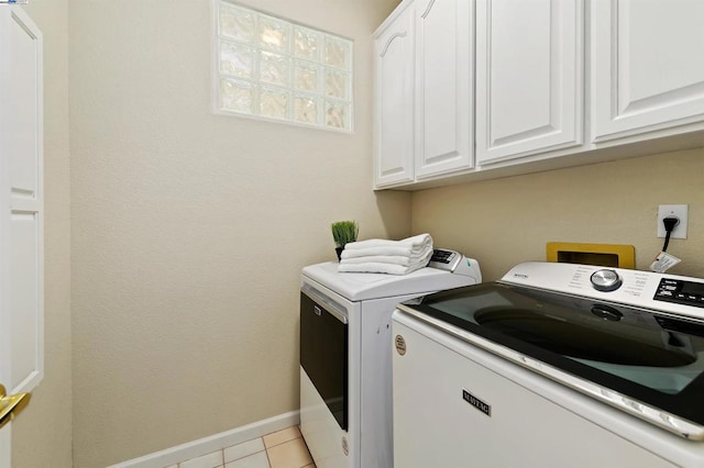 laundry room featuring cabinets, light tile patterned floors, and washer and dryer