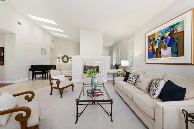 living room with a skylight, high vaulted ceiling, and a premium fireplace