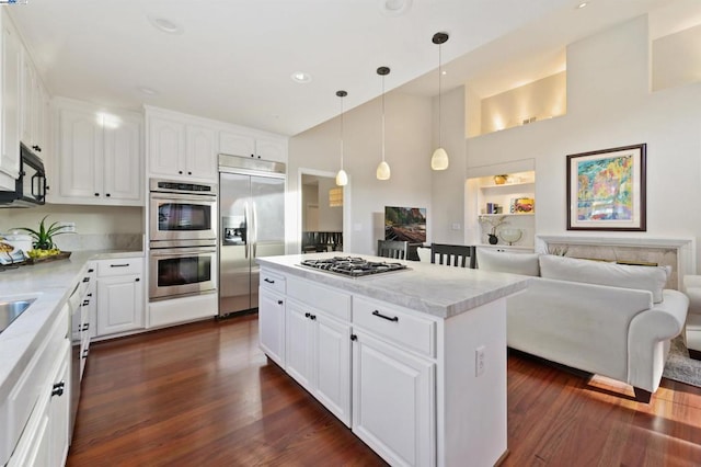 kitchen with pendant lighting, stainless steel appliances, a center island, and white cabinets