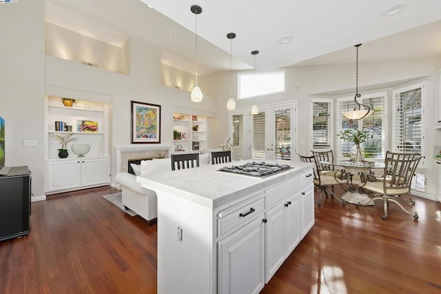 kitchen with a center island, white cabinets, built in shelves, decorative light fixtures, and stainless steel gas stovetop