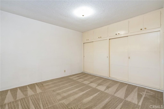 unfurnished bedroom with a textured ceiling, a closet, and light carpet