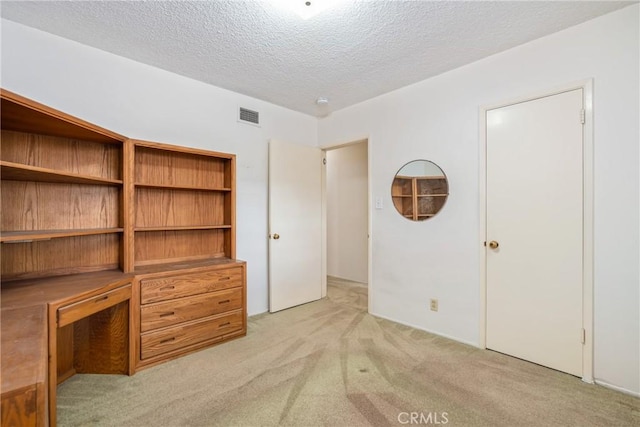 unfurnished bedroom featuring light colored carpet and a textured ceiling