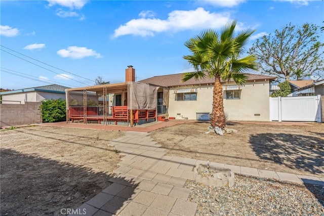 back of property with a deck and a patio