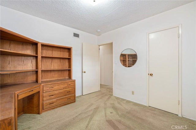 unfurnished bedroom featuring a textured ceiling and light colored carpet