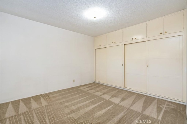 unfurnished bedroom with light carpet, a closet, and a textured ceiling