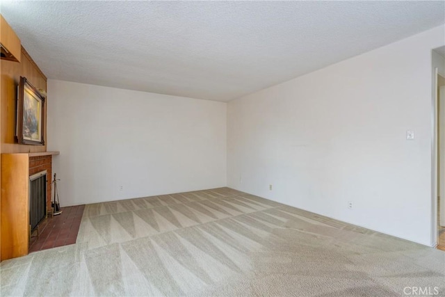 unfurnished living room with light carpet, a fireplace, and a textured ceiling