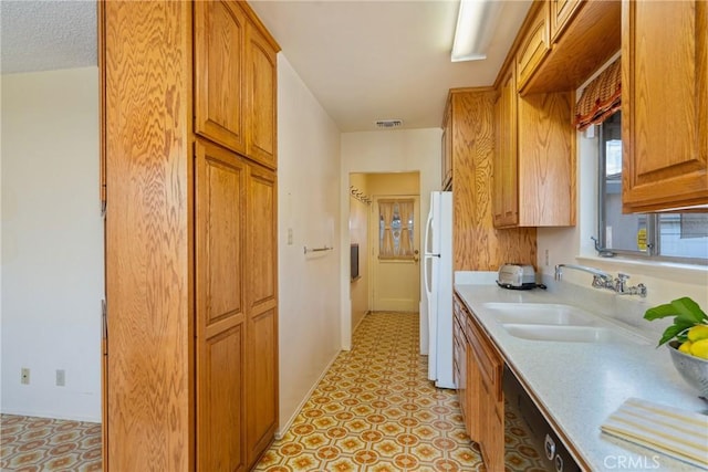 kitchen with dishwasher, sink, white fridge, and a textured ceiling