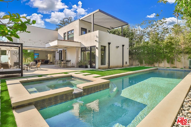 rear view of property with a pool with hot tub and a patio area