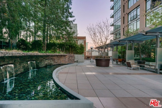 patio terrace at dusk featuring pool water feature