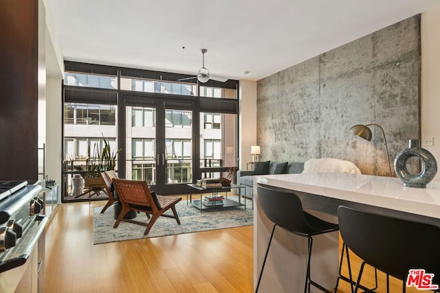 interior space with ceiling fan, expansive windows, french doors, and light hardwood / wood-style floors