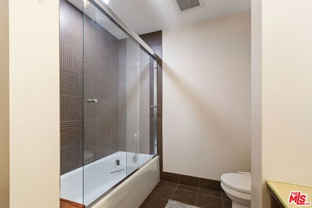 bathroom with tile patterned floors, combined bath / shower with glass door, and toilet