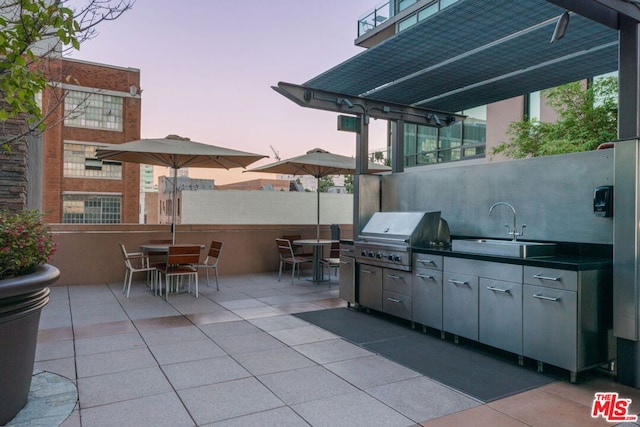 patio terrace at dusk featuring sink, a grill, and area for grilling