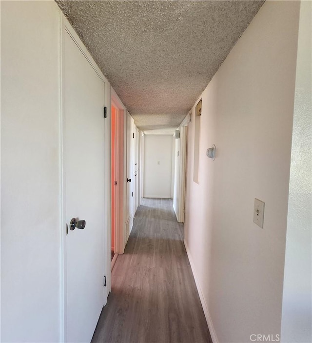 corridor featuring a textured ceiling and wood-type flooring