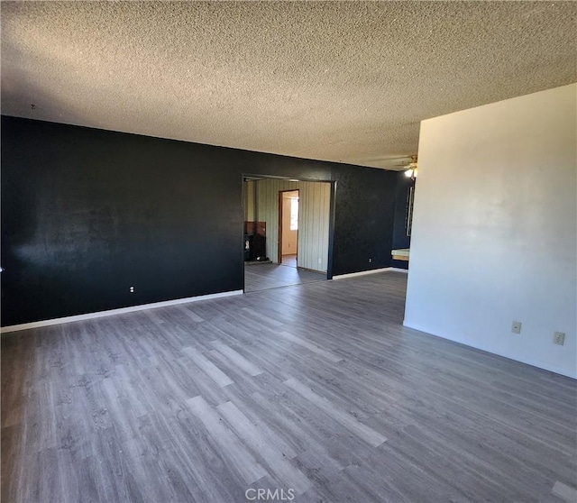 unfurnished room featuring ceiling fan, dark wood-type flooring, and a textured ceiling