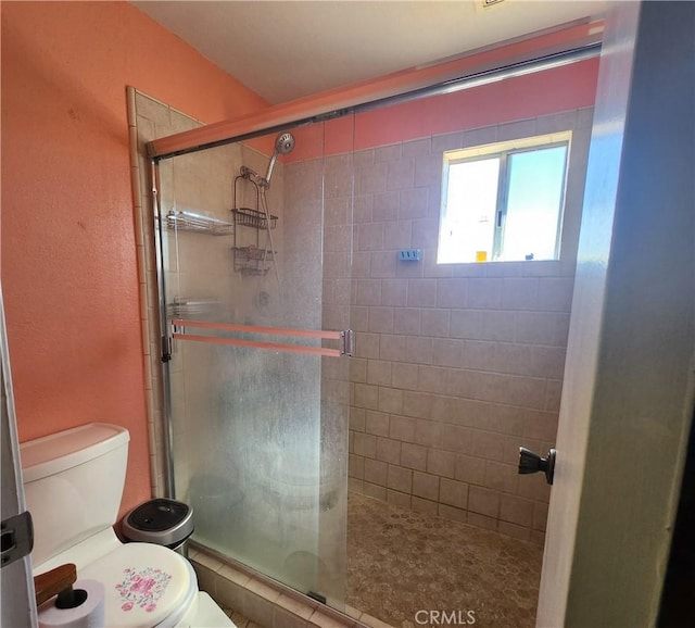 bathroom featuring toilet and a shower with door