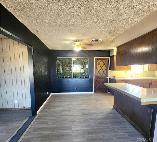 interior space featuring ceiling fan, tile countertops, and wood-type flooring