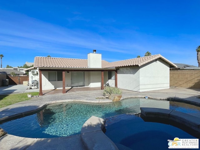 back of property with a fenced in pool and a patio