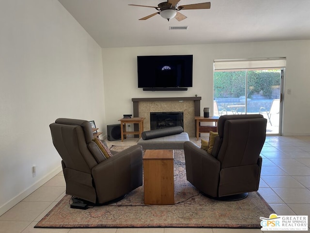 living room with ceiling fan, light tile patterned floors, and a tiled fireplace