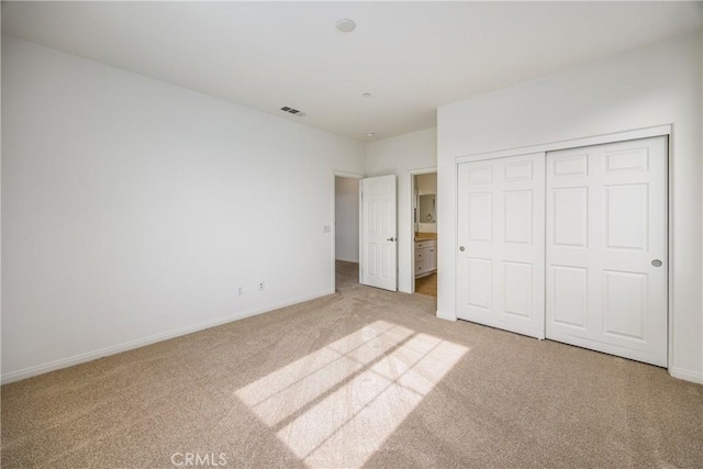 unfurnished bedroom with carpet flooring, connected bathroom, and a closet