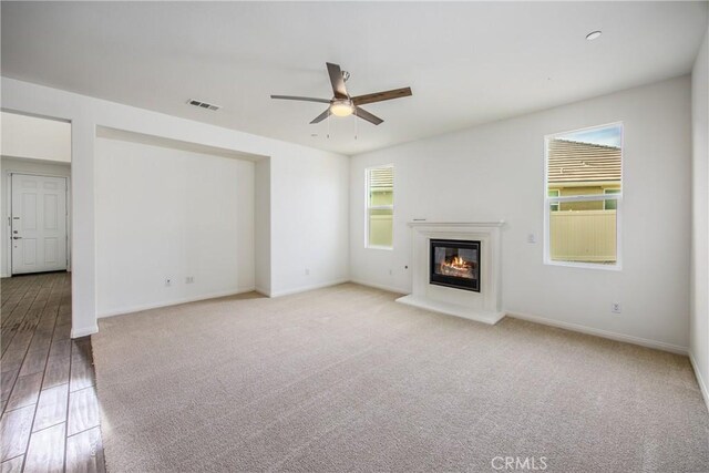 unfurnished living room with light carpet and ceiling fan