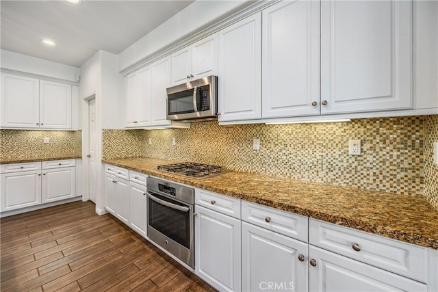 kitchen featuring dark hardwood / wood-style floors, dark stone countertops, white cabinets, decorative backsplash, and stainless steel appliances