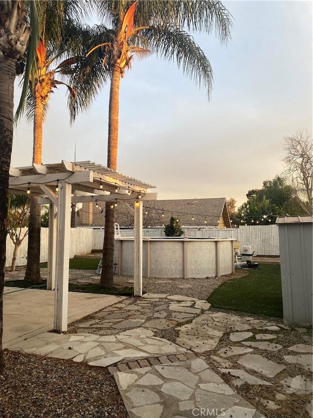 patio terrace at dusk featuring a fenced in pool and a pergola